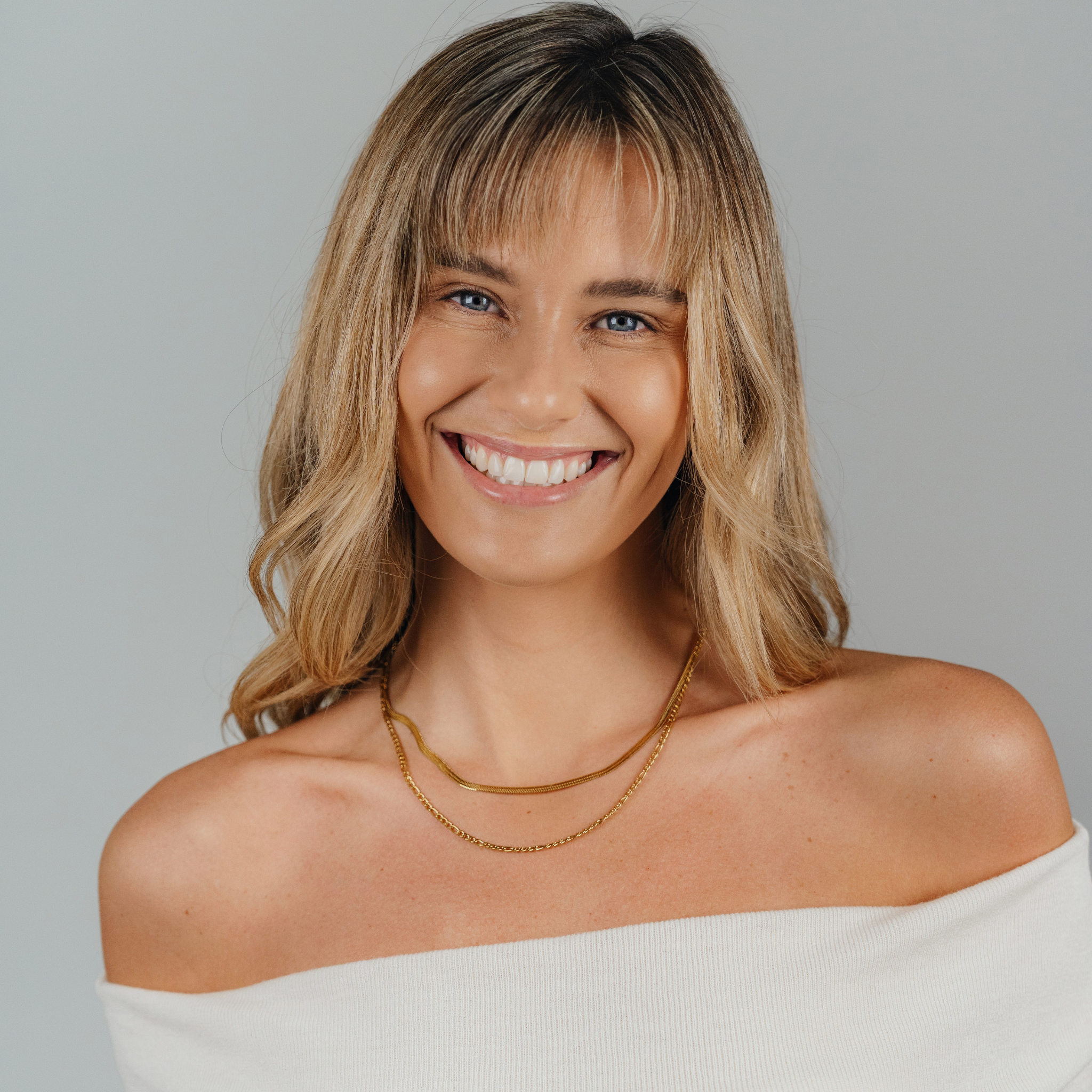 A female wearing SAAR CO's Ale, an 18K gold-plated Snake Skin Chain. She is also wearing SAAR CO's 18k gold-coated Madeline, a 3mm Figaro chain.