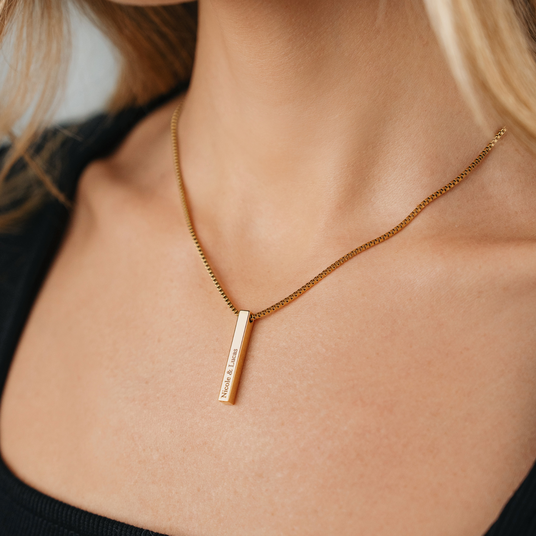 A Female wearing SAAR CO's LAUREN 18k gold-plated Stainless Steel box pendant chain. The pendant has been engraved with Nicole & Lucas.