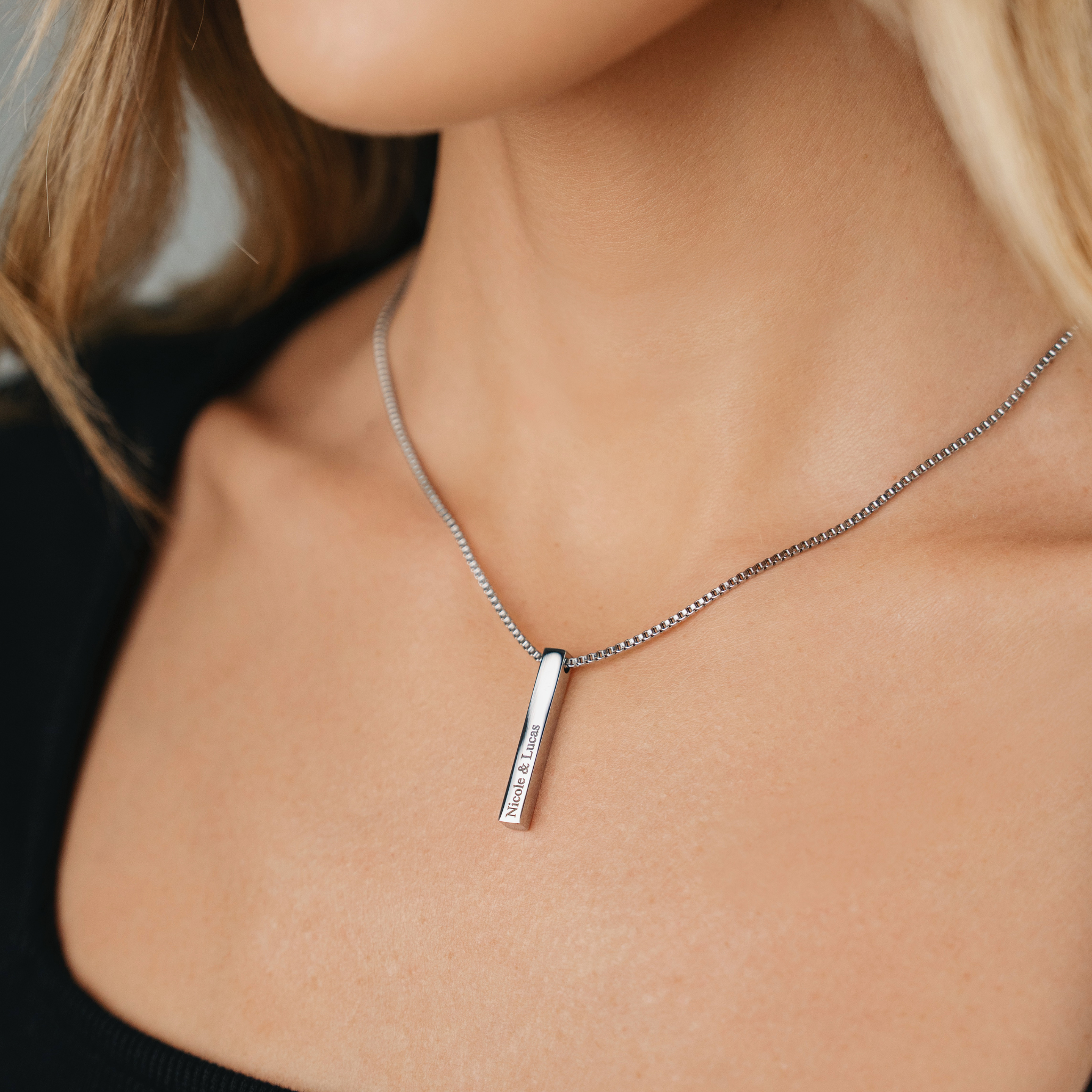 A female wearing SAAR CO's LAUREN, a Stainless Steel box pendant chain. The pendant has been engraved with Nicole & Lucas.